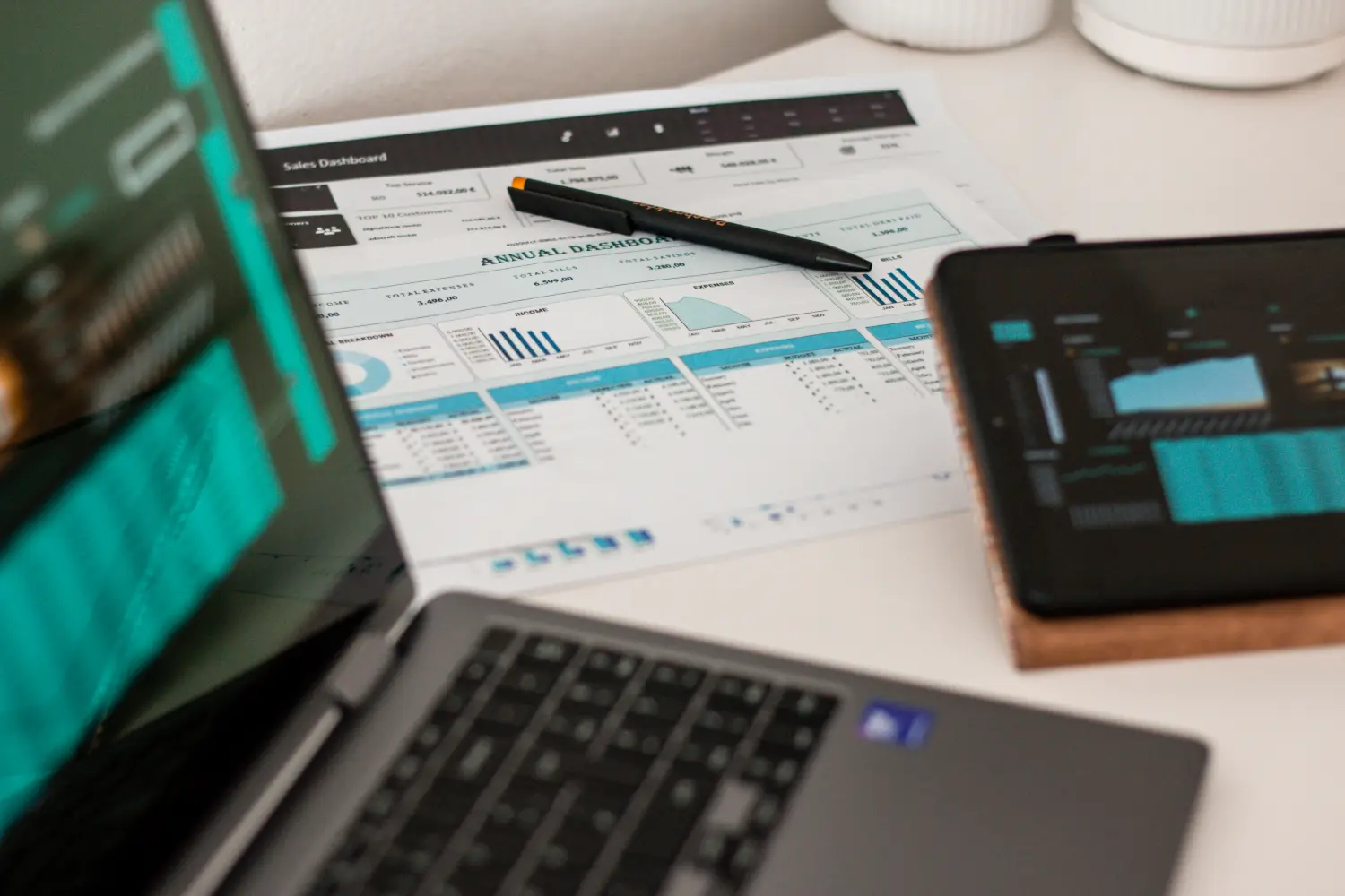 Ein Laptop mit einem Dashboard für Personalmanagement oder Business Intelligence sowie ein offener Planer oder ein Notizbuch mit Schreibutensilien suggerieren eine Arbeits- oder Lernumgebung.